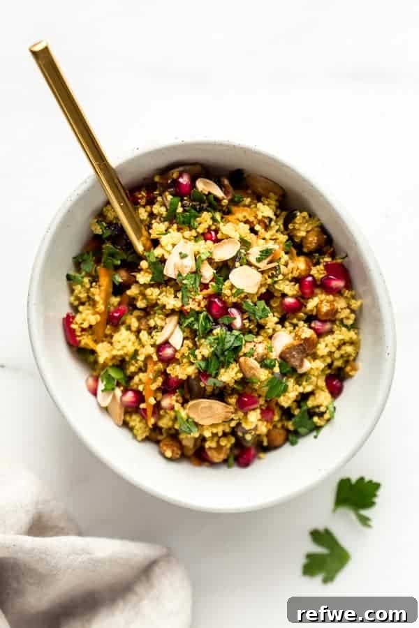 A beautifully presented bowl of Moroccan quinoa salad with a golden spoon, ready to be enjoyed.