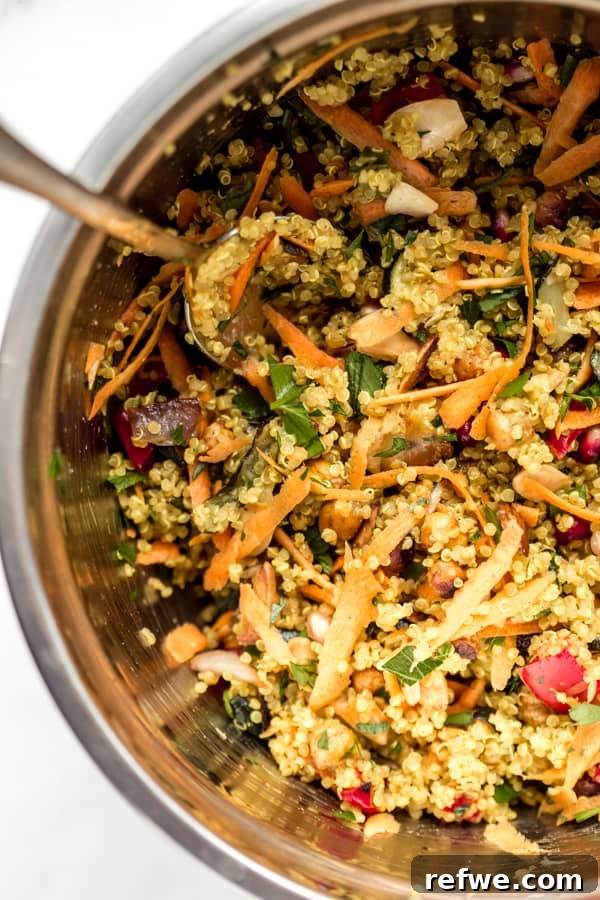 A close-up photo of the colorful Moroccan quinoa salad presented in a large metal mixing bowl, highlighting its textures and ingredients.