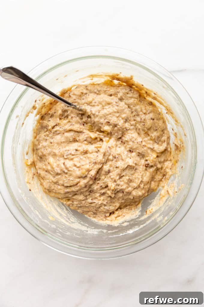 Vegan banana bread batter in a clear mixing bowl, showing a slightly lumpy but well-combined texture.