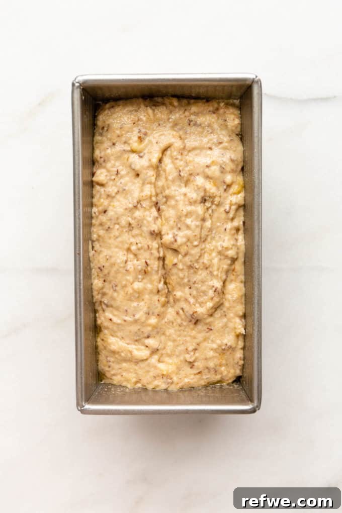 Vegan banana bread batter poured into a prepared loaf pan, ready for baking.
