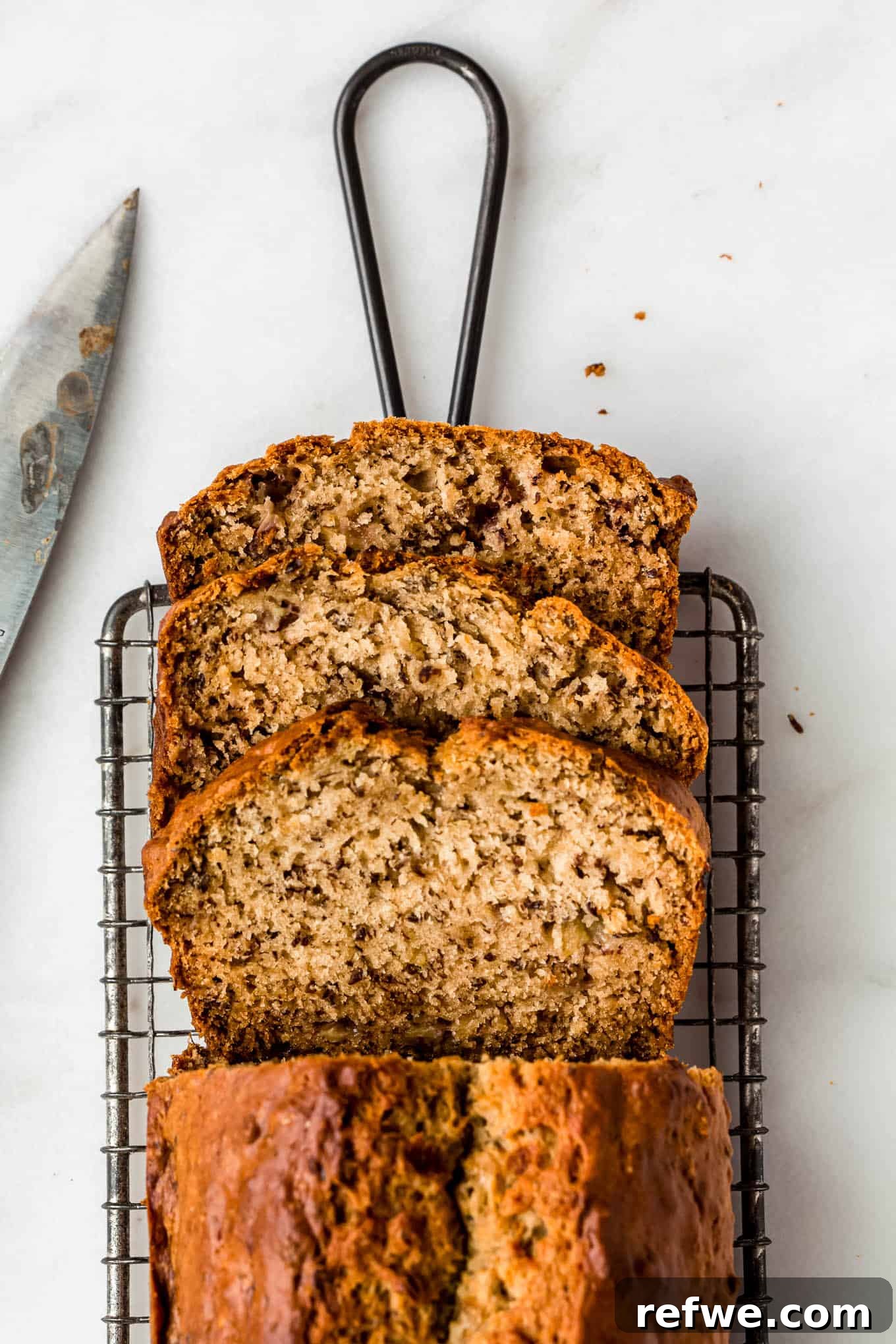 Beautifully sliced banana bread on a cooling rack, showcasing its moist texture.