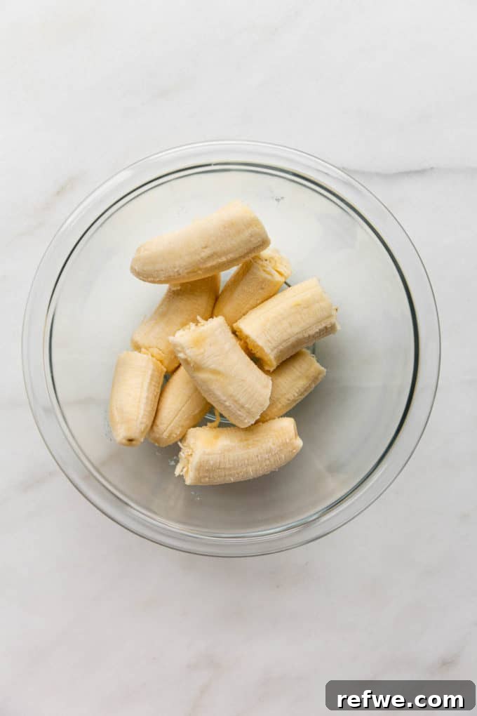 Overripe bananas being peeled into a mixing bowl, ready for mashing.