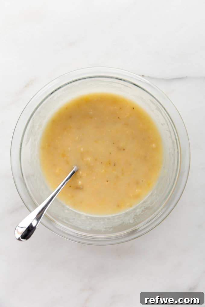 Mashed bananas, melted vegan butter, and other wet ingredients combined in a bowl.