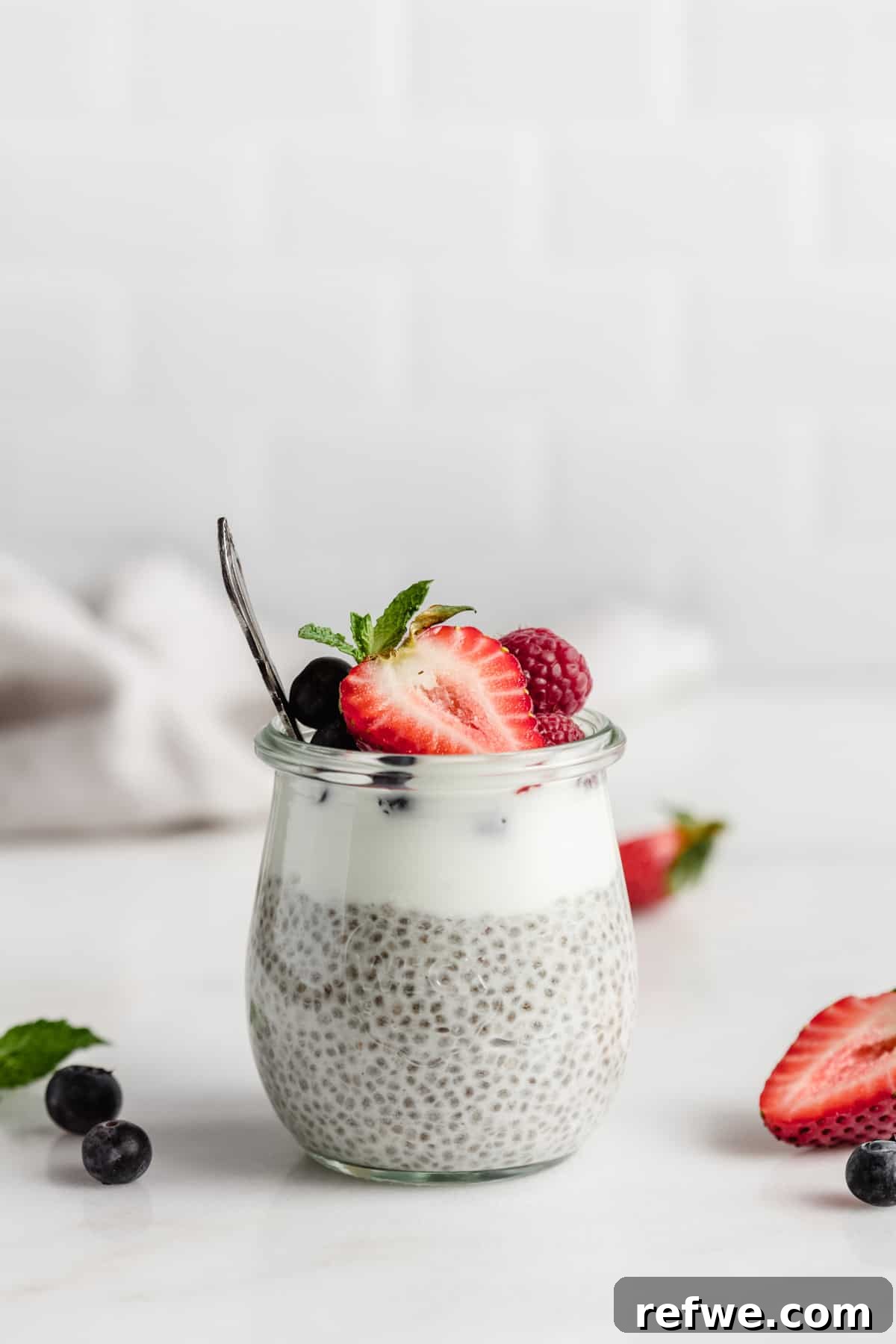 Creamy Vanilla Chia Delight 8 One small cup of vanilla chia pudding topped with fresh berries and a spoon, inviting you to try it.