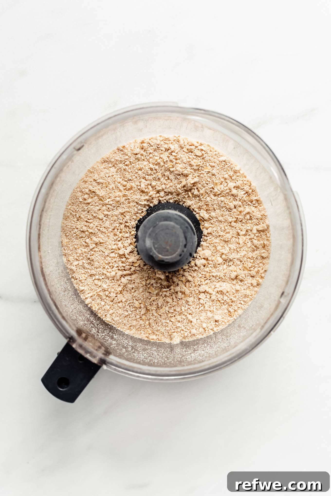 Gluten-free crisp topping ingredients, including oats, almond flour, and vegan butter, being pulsed in a food processor to form a crumbly mixture.