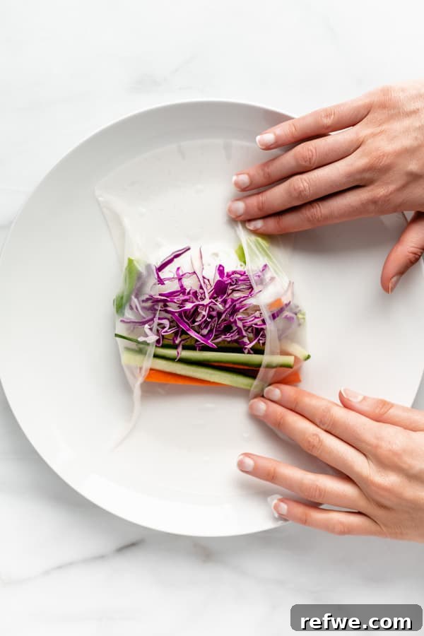 Summer Rolls 6 Two hands demonstrate the technique of rolling a Vietnamese summer roll, tucking in ingredients tightly.