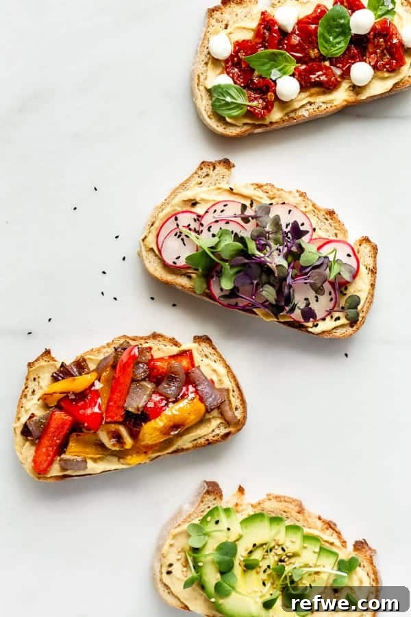Effortless Hummus Toast Explorations 6 A stunning visual of four distinct hummus toasts, each adorned with vibrant, colorful toppings, presented artfully on a rustic wooden board, showcasing the finished creations.