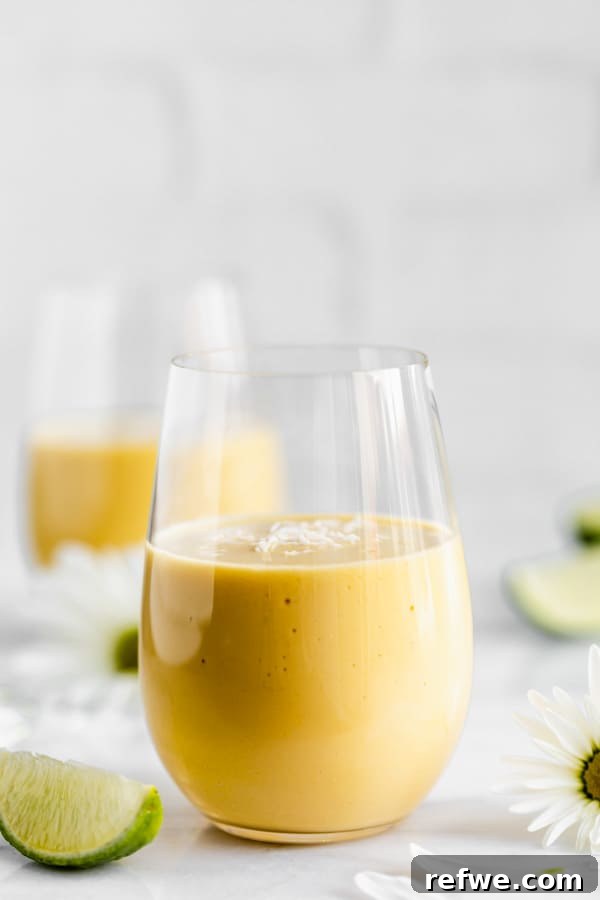 a glass of vegan mango lassi with shredded coconut on top