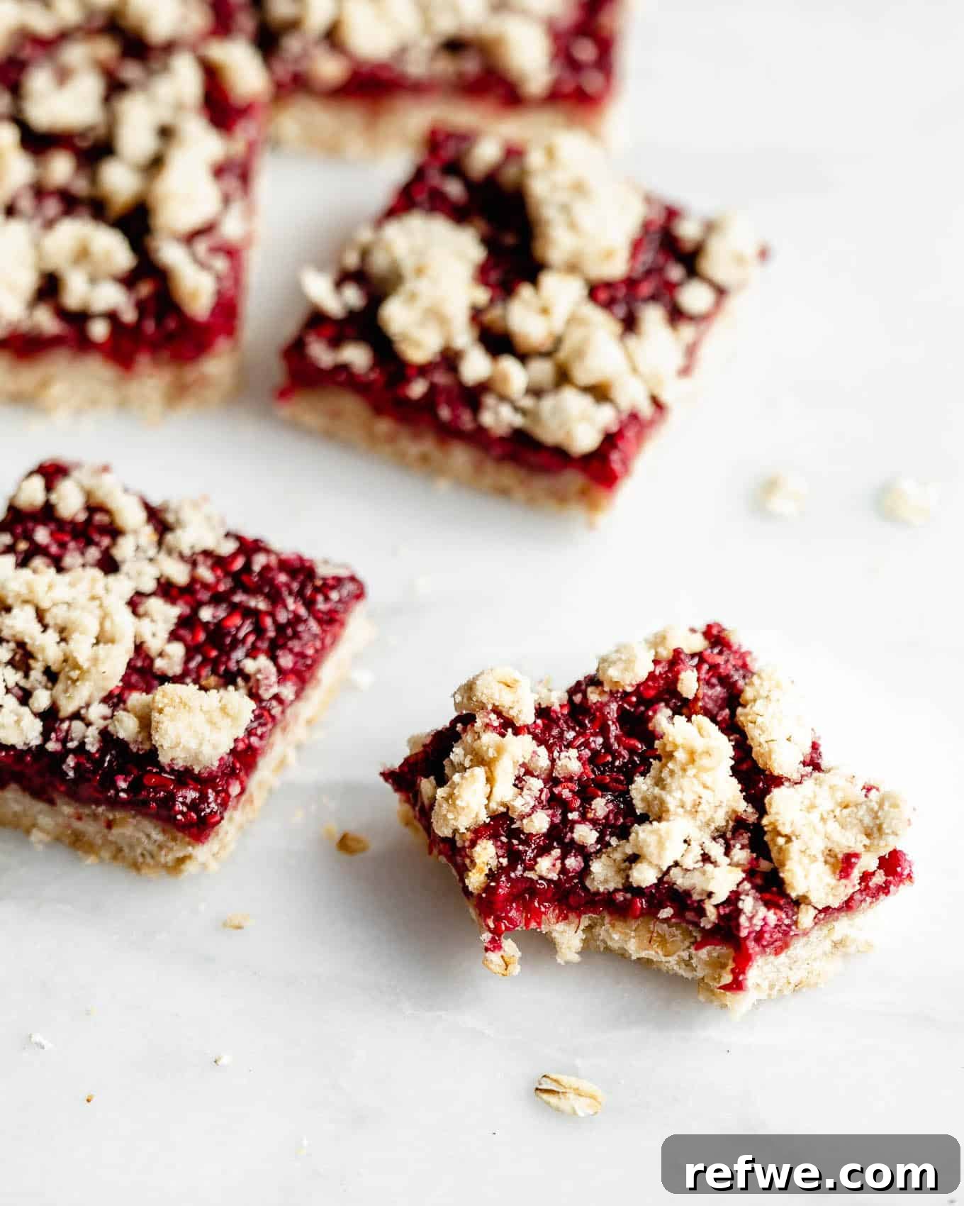 Golden Raspberry Crumble Bars 8 Beautifully arranged raspberry crumble bars on a marble board, showcasing their golden crust and vibrant filling.