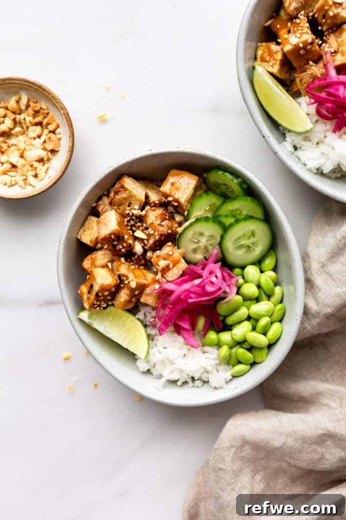 Peanut Tofu Power Bowls 2 A vibrant Peanut Tofu Buddha Bowl featuring crispy tofu, fresh cucumber, green edamame, and tangy pickled onions, served over fluffy rice with a drizzle of rich peanut sauce.