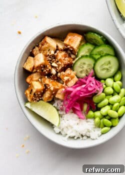 a peanut tofu bowl with cucumber, edamame and pickled onions