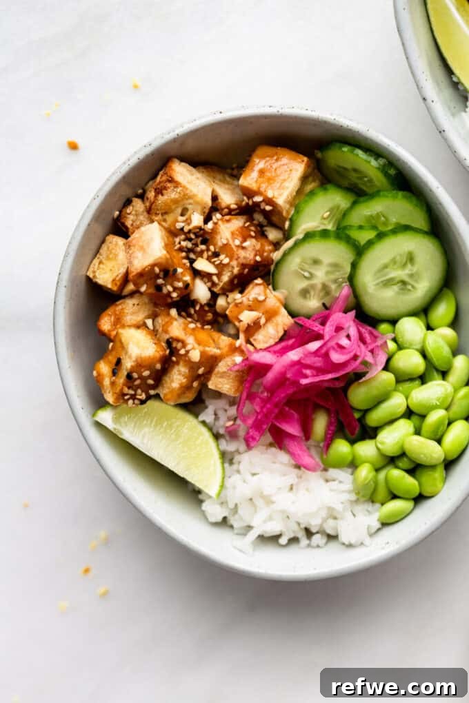 Peanut Tofu Power Bowls 10 A close-up shot of a single peanut tofu bowl, showcasing the intricate layering of crispy tofu, refreshing cucumber, vibrant edamame, and tangy pickled onions, all glistening with rich peanut sauce.