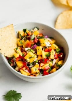 a bowl of mango salsa with a tortilla chip in it