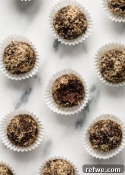chocolate date balls covered in crushed walnuts on a marble counter
