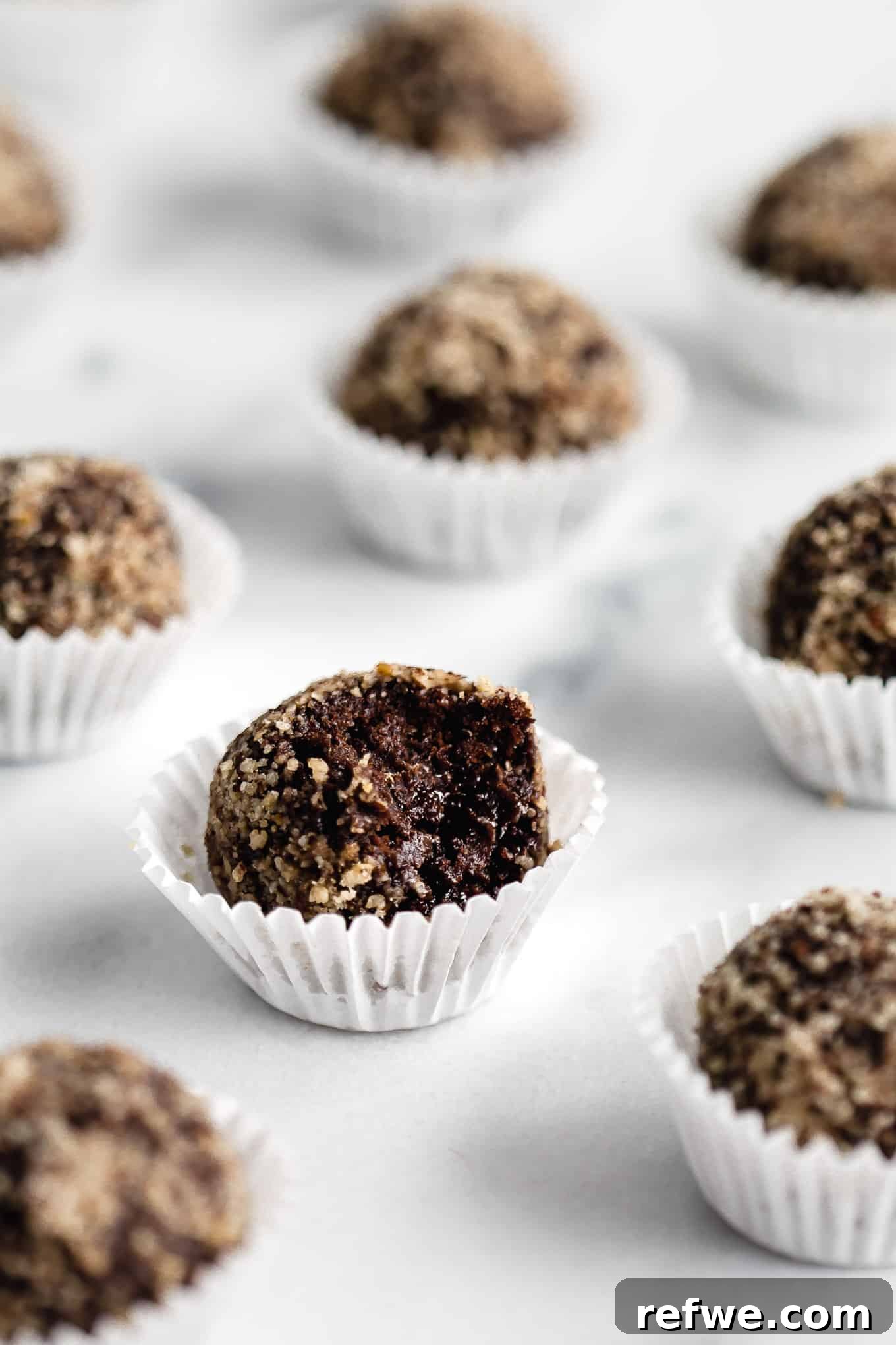 Fudgy Date & Chocolate Bites 7 Six chocolate date balls presented neatly in mini muffin liners, ready for serving or storage.