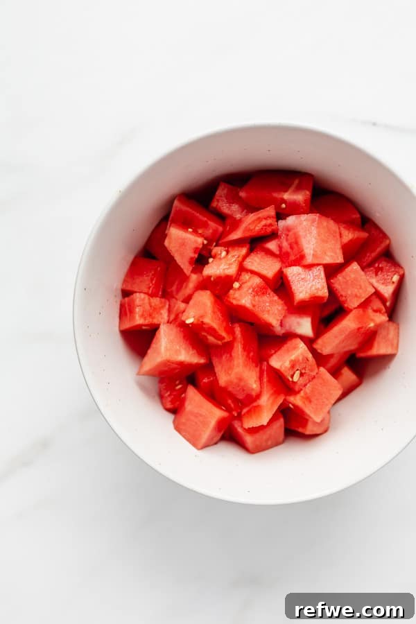 Minty Watermelon Feta Fusion 3 Freshly cut watermelon cubes neatly arranged in a rustic wooden bowl, showcasing their vibrant red color and juicy texture.
