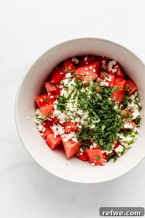 Minty Watermelon Feta Fusion 4 Freshly cubed watermelon, crumbled feta cheese, and fragrant mint leaves ready to be combined in a mixing bowl for a refreshing salad.