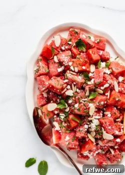 A platter with watermelon feta salad topped with mint and almonds