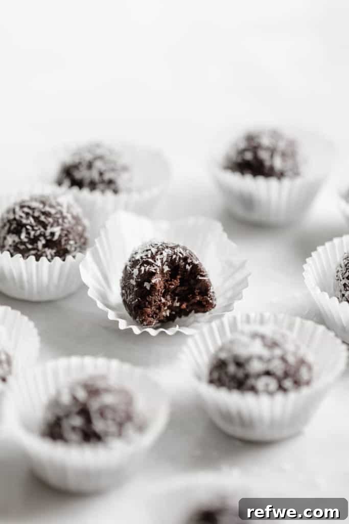 Effortless Oven-Free Sweet Treats 11 Several no-bake tahini chocolate date balls, dusted with cocoa powder, arranged on a marble board.