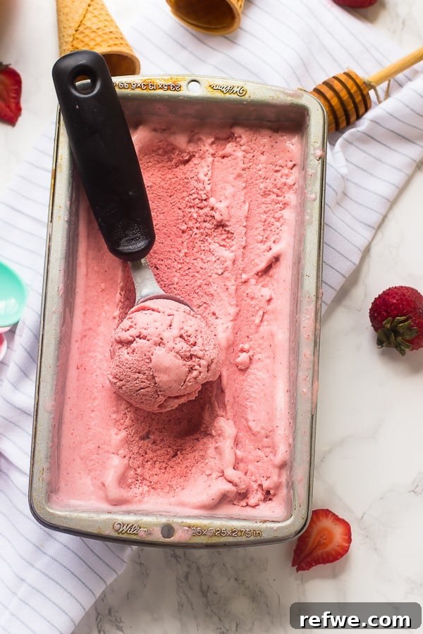 Effortless Oven-Free Sweet Treats 16 Creamy vegan strawberry ice cream in a tray with an ice cream scoop, ready to be served.