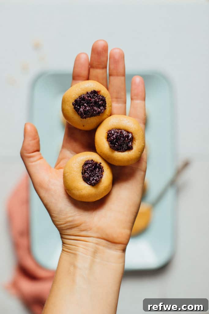 Effortless Oven-Free Sweet Treats 4 A hand holds three golden-brown peanut butter thumbprint cookies, each with a visible indentation.