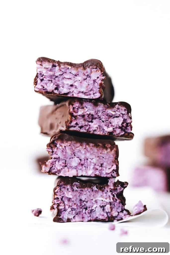 Effortless Oven-Free Sweet Treats 7 A stack of four blackberry coconut bars, showing the purple berry layer and white coconut base.