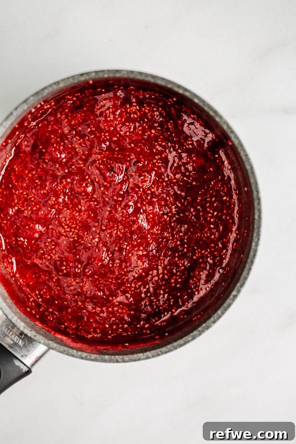 Homemade Chia Seed Jam Made Easy 4 Close-up of vibrant red chia seed jam simmering in a pot, showcasing the thickening texture as the chia seeds work their magic.