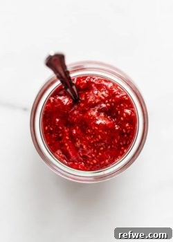 A jar of homemade chia seed jam, showcasing its appealing texture and vibrant color, ready to be served.