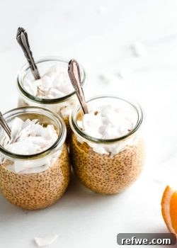 Three jars of creamsicle chia pudding with spoons and shredded coconut in them