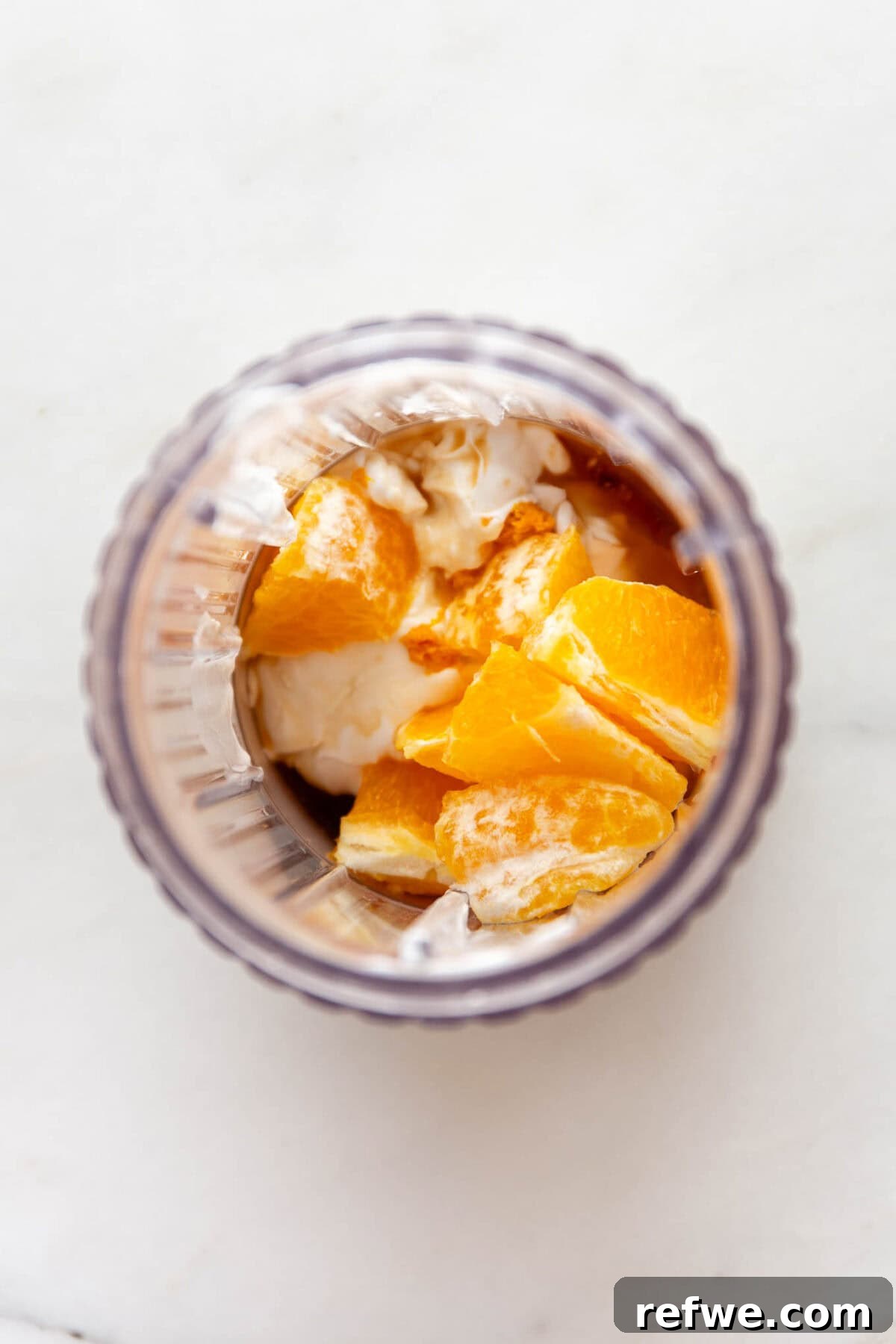 Silky Orange Dream Chia Pudding 4 Oranges, coconut milk, vanilla extract, and maple syrup are placed in a blender container, ready to be blended.