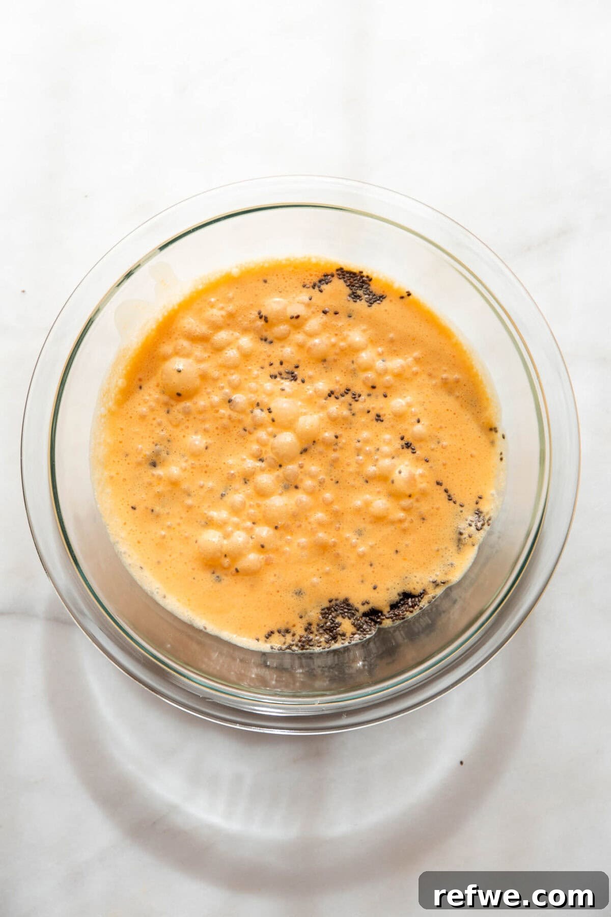 Silky Orange Dream Chia Pudding 6 The smooth, blended orange and coconut milk mixture is poured into a clear mixing bowl, with chia seeds added.