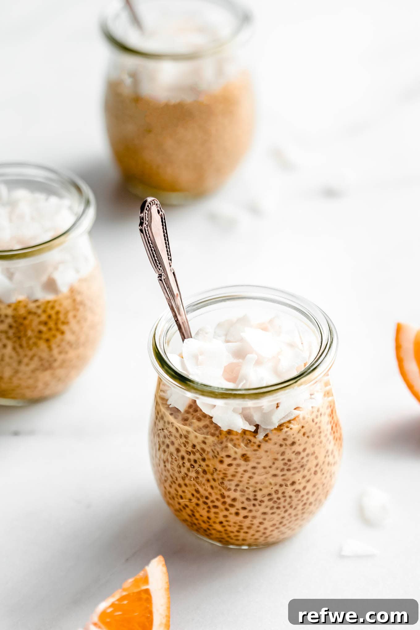 Silky Orange Dream Chia Pudding 10 A single jar of orange creamsicle chia pudding with a spoon in it, ready to be enjoyed.