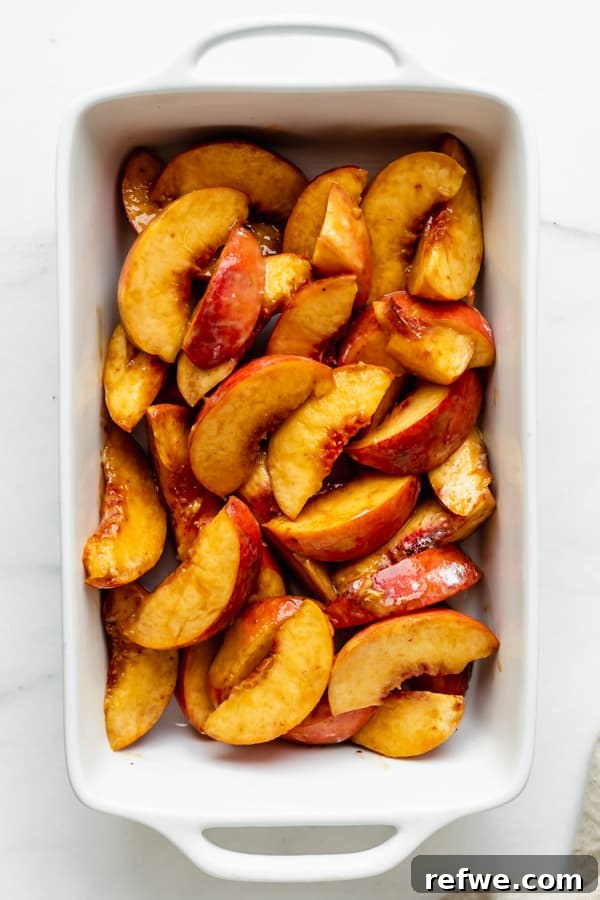 Luscious Gluten-Free Peach Cobbler 3 Sliced fresh peaches evenly spread in a white baking dish, ready for the cobbler topping.