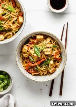 A ceramic bowl filled with bright Singapore noodles and chopsticks on the side, highlighting the dish's fresh appeal.