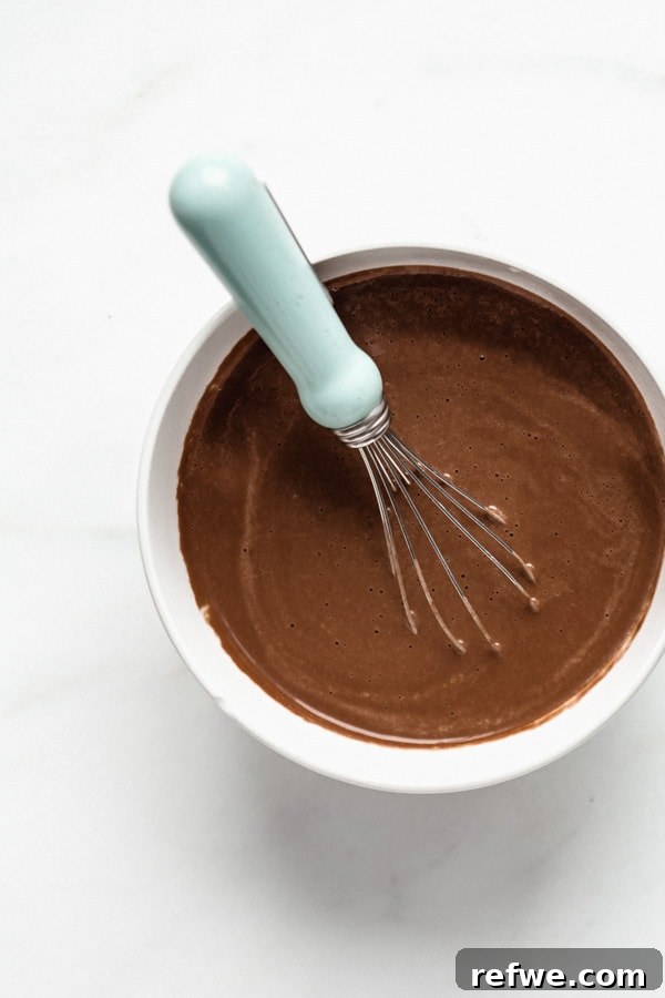 Decadent Chocolate Raspberry Chia Pudding 4 A bowl of chocolate cashew milk with a small whisk, showing it's being mixed to ensure smooth consistency before adding chia seeds.