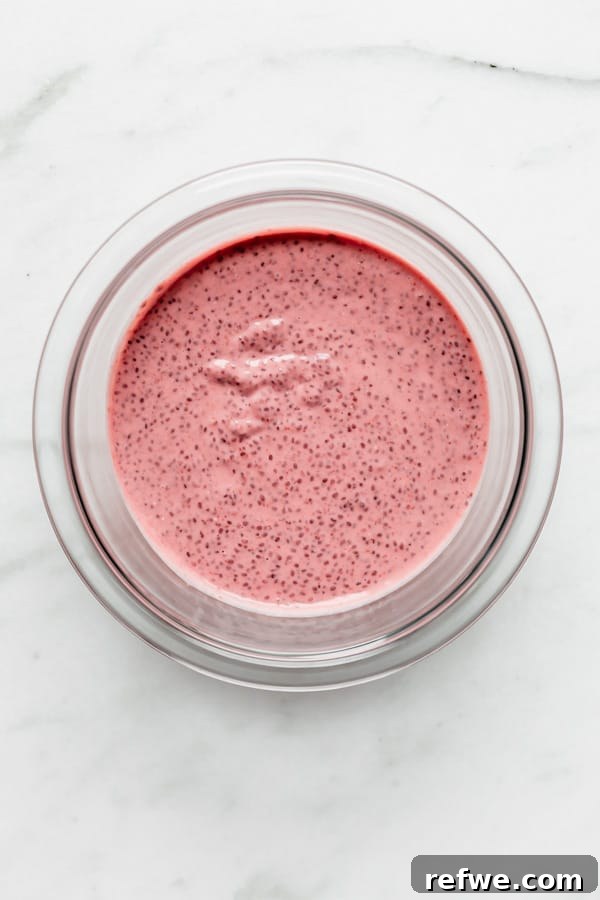 Decadent Chocolate Raspberry Chia Pudding 8 A clear mixing bowl containing thick, pink raspberry chia pudding, showcasing its perfect texture after setting.