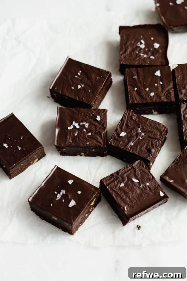 Decadent No-Bake Fudge Brownies 2 raw chocolate brownies cut up in squares on parchment paper