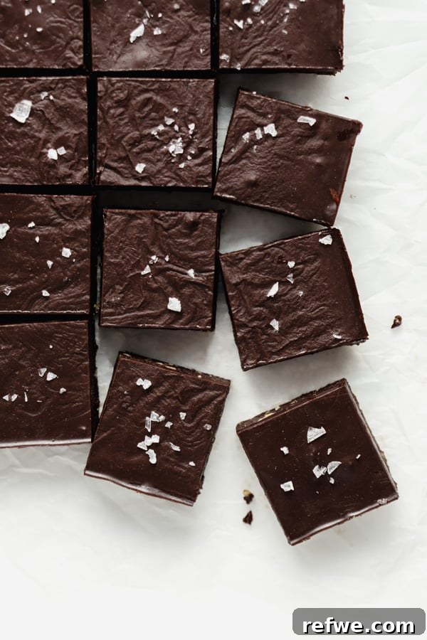 Decadent No-Bake Fudge Brownies 10 a top down image of raw chocolate brownies cut into squares on a piece of parchment paper