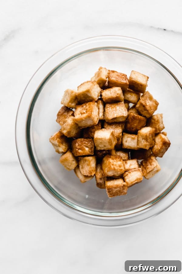Beautifully cooked, golden-brown tofu cubes, crispy on the outside and tender within, served enticingly in a clear bowl.