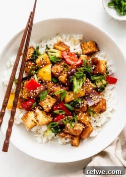 a bowl of tofu stir fry with veggies served over rice