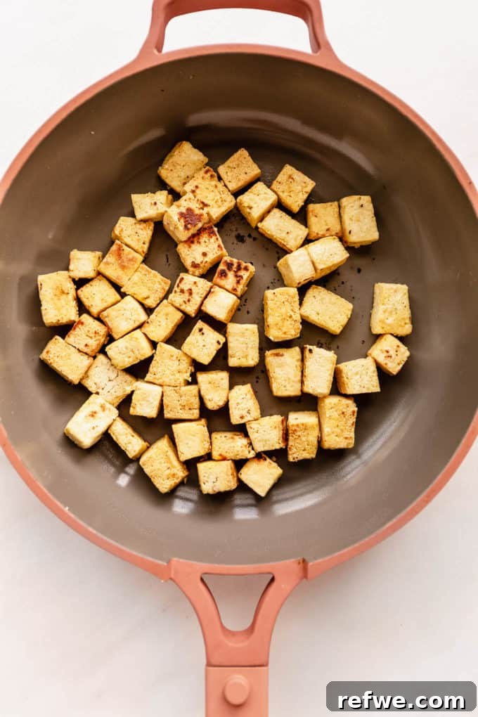 Perfectly crispy, golden-brown tofu cubes cooking in a hot pan.