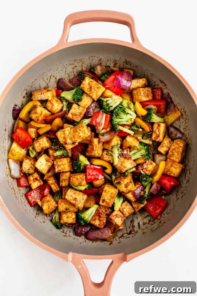 Finished tofu stir fry simmering in a pan, coated in a rich, glossy sauce.