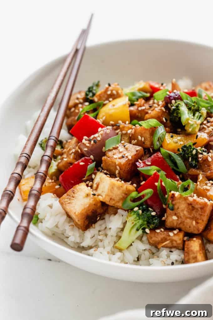 A beautifully presented bowl of tofu stir fry, served with wood chopsticks, highlighting the crispy tofu and colorful vegetables.