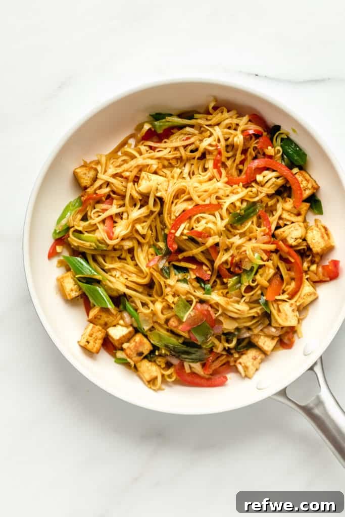25 Delicious Vegan Dinners Made Easy 3 Vibrant Vegan Singapore Noodles stir-fried in a large pan, ready to serve