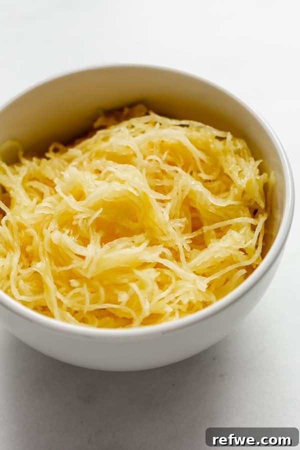 Golden Spaghetti Squash with Tangy Sun-Dried Tomatoes and Sweet Caramelized Onions 3 A close-up of shredded spaghetti squash in a bowl, resembling pasta strands.