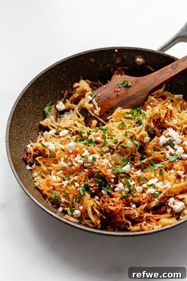 Golden Spaghetti Squash with Tangy Sun-Dried Tomatoes and Sweet Caramelized Onions 5 A large pan filled with sun-dried tomato spaghetti squash, caramelized onions, and pesto, ready to serve.