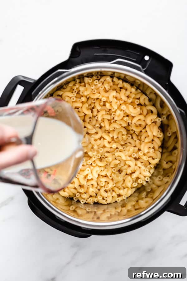 Quick Creamy Instant Pot Mac and Cheese 5 mac and cheese in an instant pot with milk being poured in it