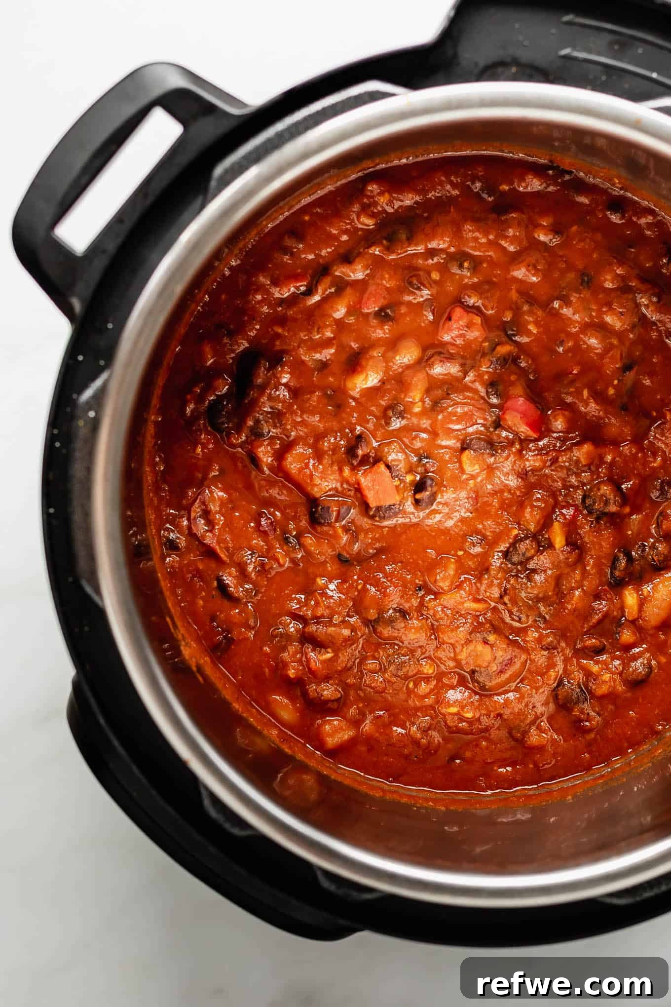 An Instant Pot filled with a rich, dark red vegan chili, ready to be served.