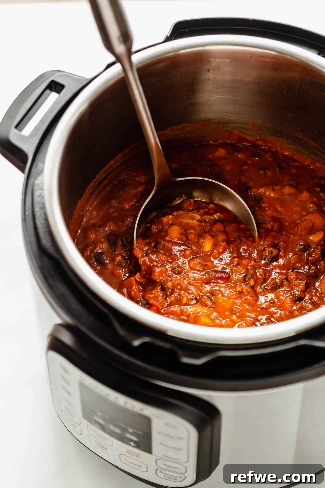 A close-up shot of vegan chili simmering in a slow cooker, showcasing its rich texture and inviting warmth.
