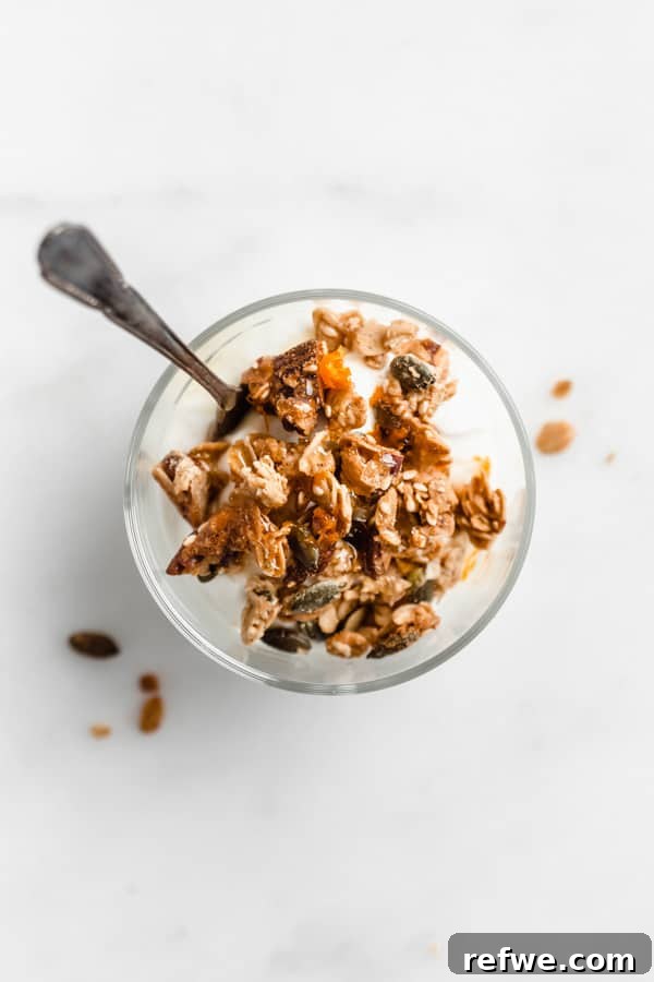 Citrus Cardamom Tahini Granola Crunch 8 A top-down view of a cup of yogurt topped with a generous portion of orange cardamom tahini granola, presented beautifully.